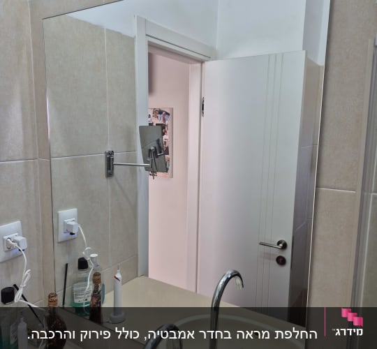 מראה בחדר אמבטיה עם כיור וברזים